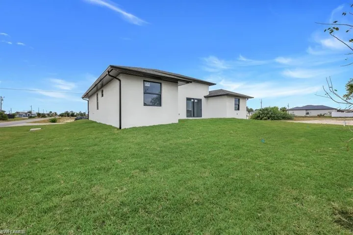 Rear view of house with a lawn and stucco siding
