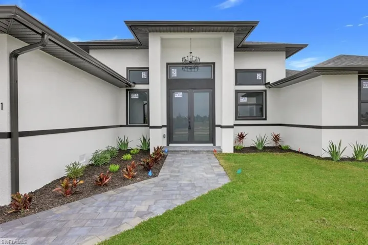 View of exterior entry featuring stucco siding and a yard