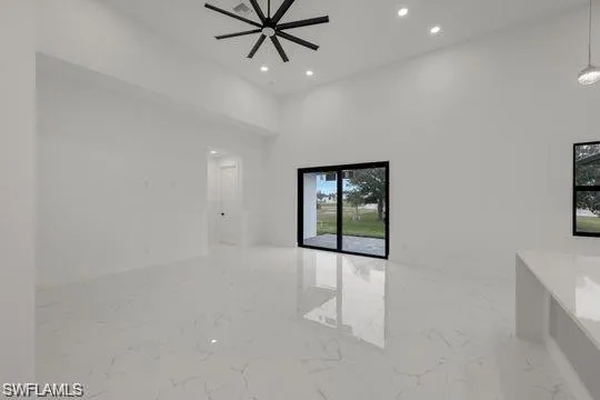 Spare room with marble tiled floors, recessed lighting, ceiling fan, and a high ceiling