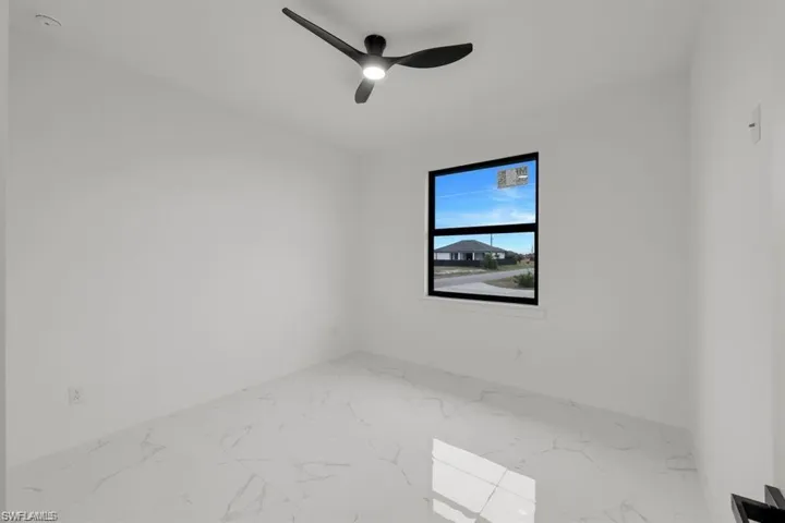 Spare room with marble finish flooring and a ceiling fan