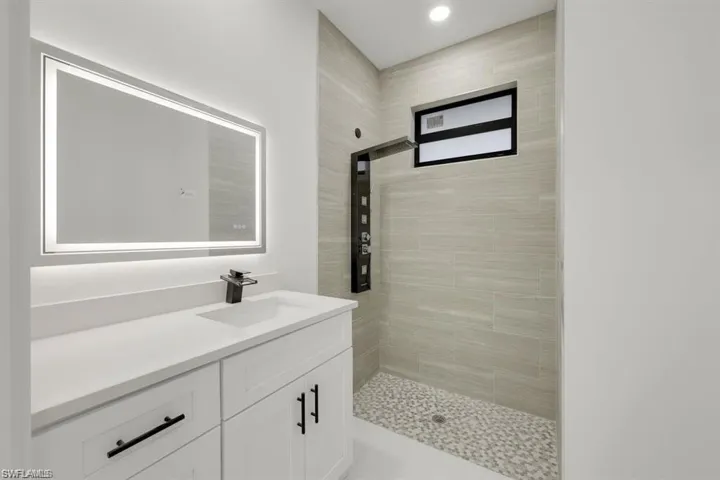 Full bath featuring vanity, a tile shower, and recessed lighting