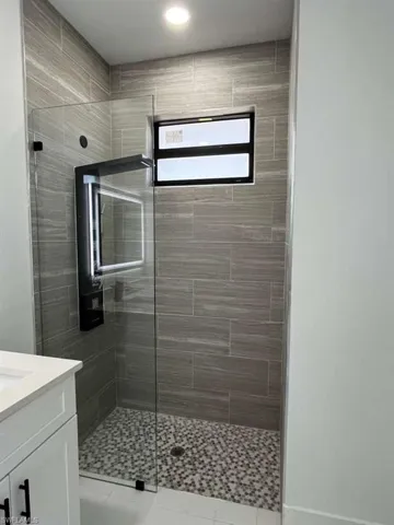 Full bath featuring a tile shower and vanity
