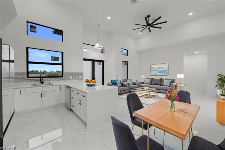 Kitchen featuring white cabinets, light stone countertops, a high ceiling, a peninsula, and tasteful backsplash