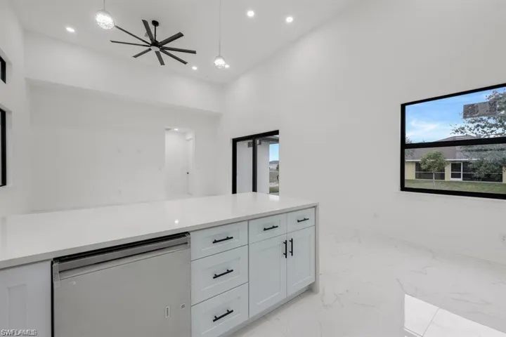 Kitchen with white cabinets, light marble finish flooring, recessed lighting, hanging light fixtures, and light countertops