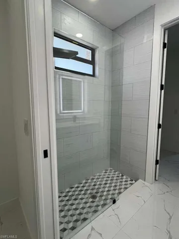 Full bath with light marble finish floors and a stall shower