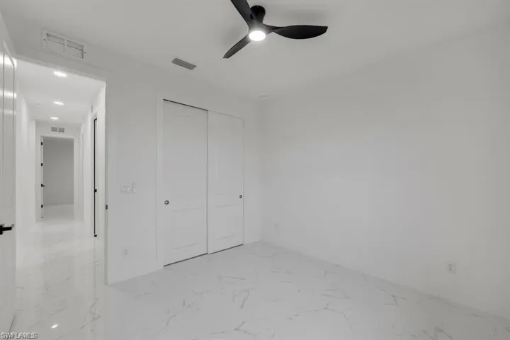 Unfurnished bedroom with light marble finish floors, a closet, recessed lighting, and a ceiling fan