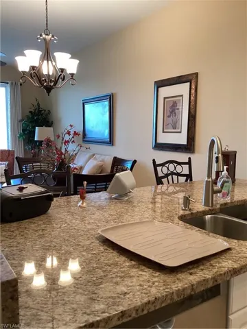 Kitchen with decorative light fixtures, a chandelier, sink, and stone counters