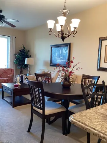 Dining area with carpet flooring and ceiling fan with notable chandelier