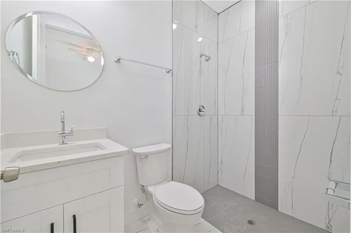 Bathroom with tiled shower, vanity, and toilet