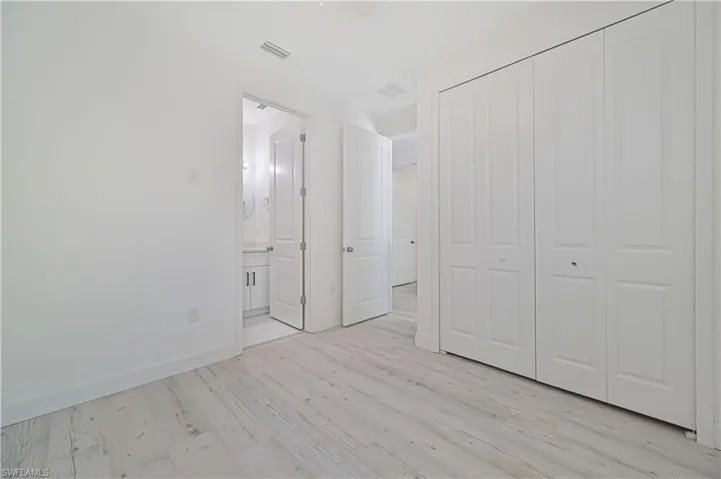 Unfurnished bedroom with light hardwood / wood-style flooring, a closet, and ensuite bathroom