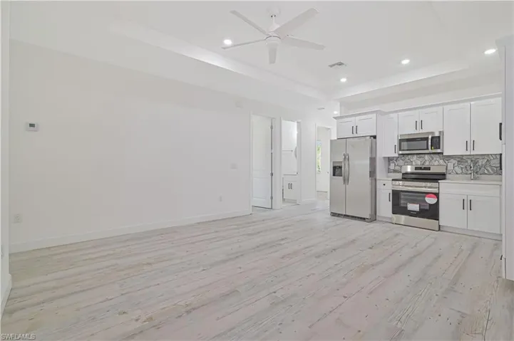 Kitchen featuring appliances with stainless steel finishes, light hardwood / wood-style floors, white cabinetry, and ceiling fan