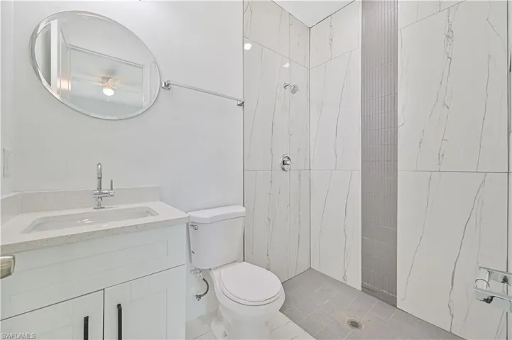 Bathroom with tiled shower, vanity, and toilet