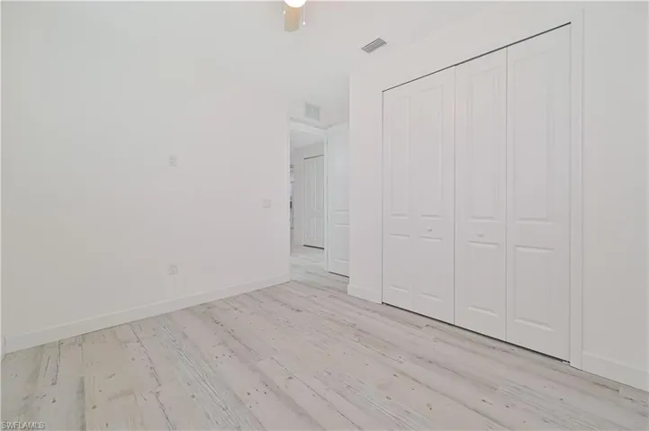 Unfurnished bedroom with light wood-type flooring, ceiling fan, and a closet