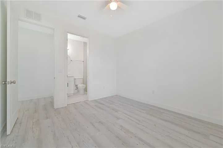 Unfurnished bedroom featuring light hardwood / wood-style flooring, ceiling fan, and ensuite bathroom
