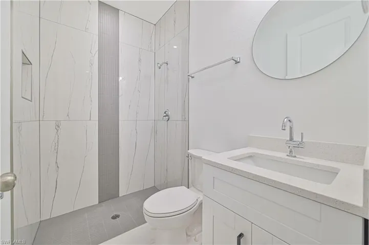 Bathroom featuring vanity, toilet, and tiled shower