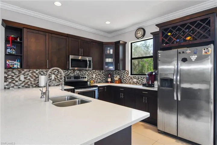 Kitchen featuring stainless steel appliances, a sink, dark brown cabinets, decorative backsplash, and light countertops