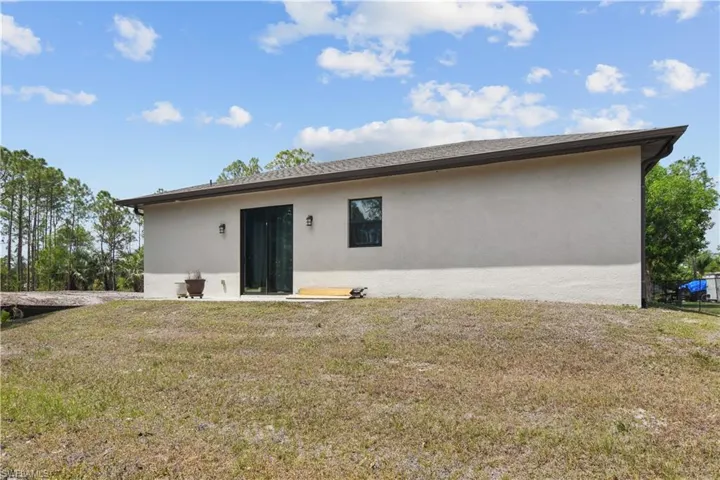 Rear view of property with stucco siding and a yard