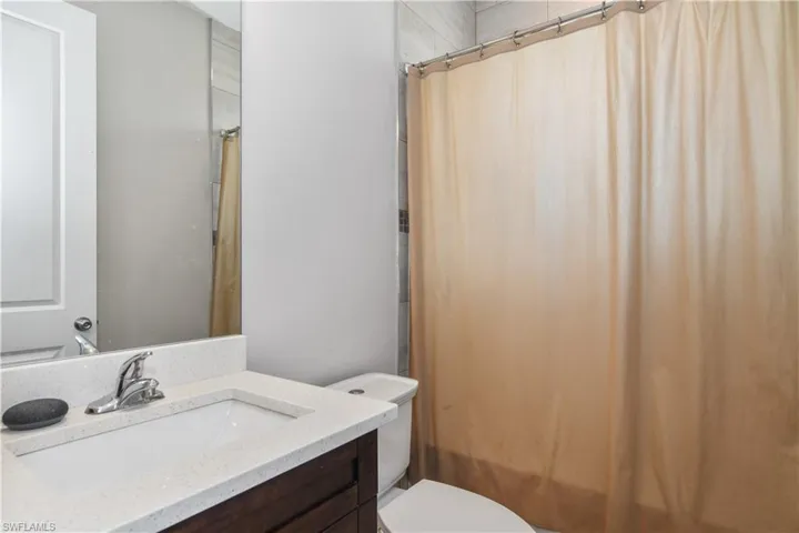 Bathroom with toilet, vanity, and shower / bathtub combination with curtain