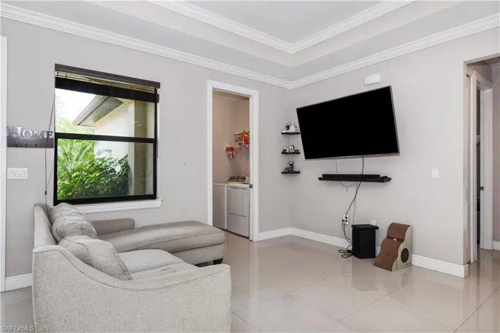 Living area featuring baseboards, crown molding, washer and clothes dryer, and light tile patterned floors