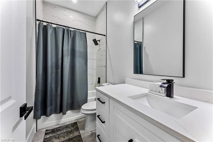 Full bathroom featuring tile floors, shower / bath combo, toilet, and vanity