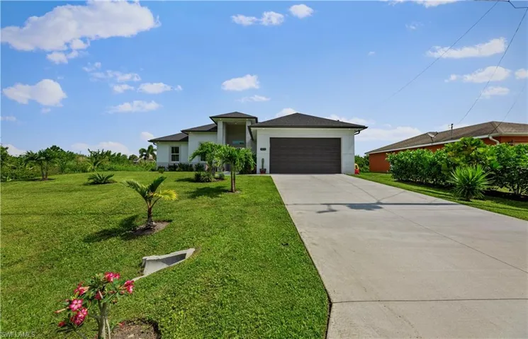 Single story home featuring a garage and a front lawn