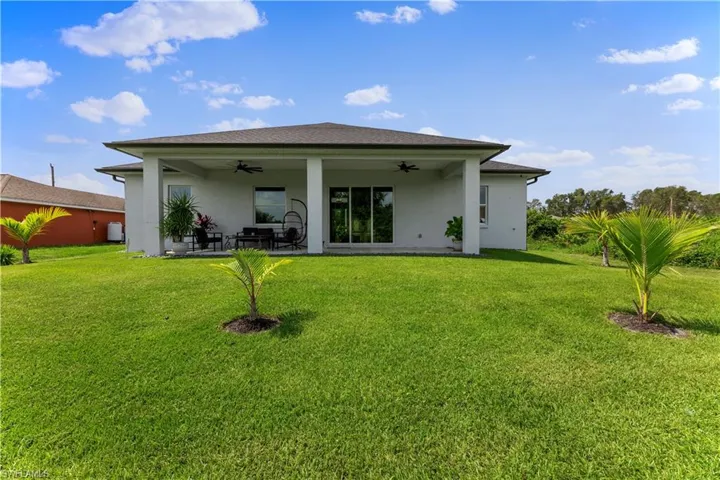 Rear view of house featuring a patio, ceiling fan, and a lawn