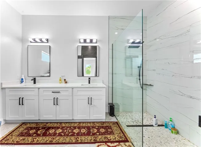 Bathroom featuring double vanity, tile flooring, and a shower with door