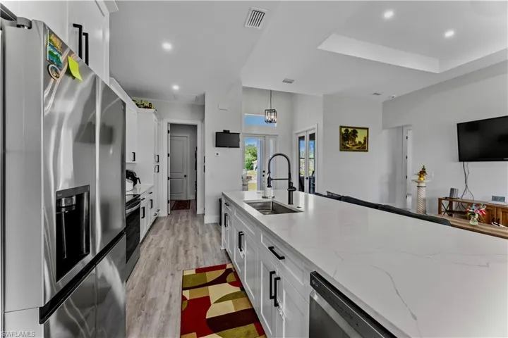 Kitchen featuring stainless steel appliances, light hardwood / wood-style flooring, white cabinets, and sink