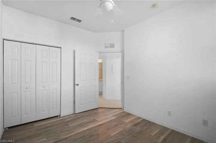 Unfurnished bedroom with dark wood-type flooring, a closet, and a ceiling fan