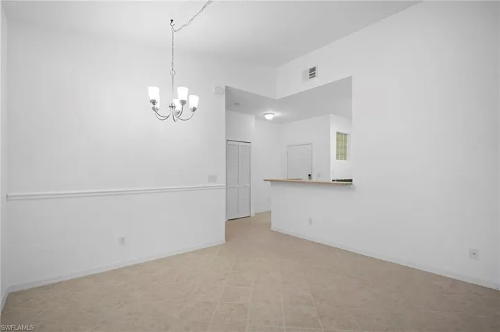 Spare room featuring baseboards and a chandelier