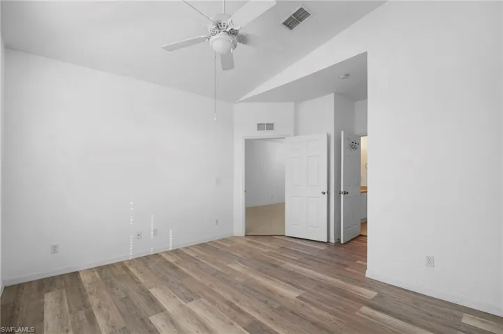 Unfurnished room with vaulted ceiling, wood finished floors, and a ceiling fan