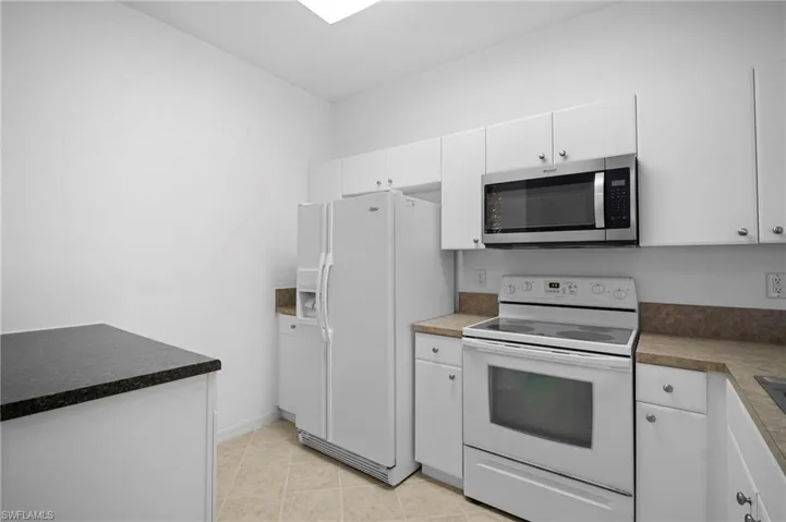 Kitchen featuring white appliances, white cabinets, and light tile patterned floors