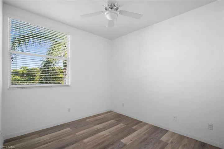 Unfurnished room featuring dark wood-type flooring and a ceiling fan