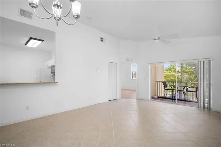 Empty room with a high ceiling, a chandelier, ceiling fan, and light tile patterned floors