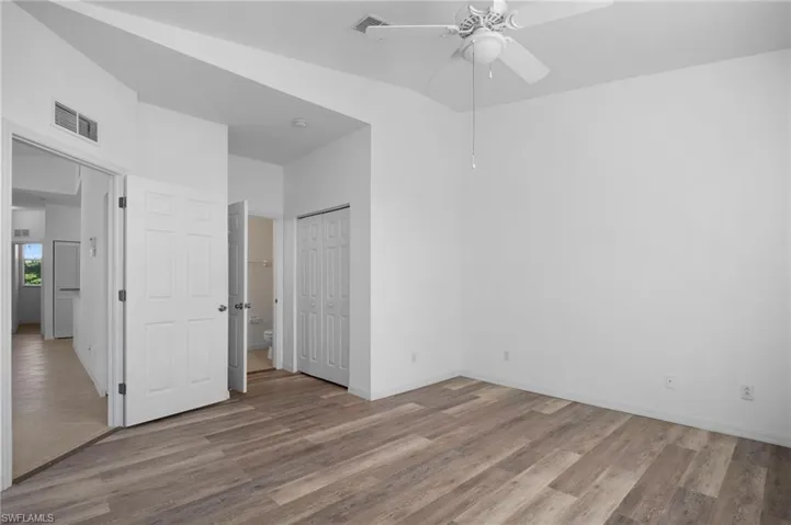 Unfurnished bedroom with light wood-style floors, a ceiling fan, a closet, and connected bathroom