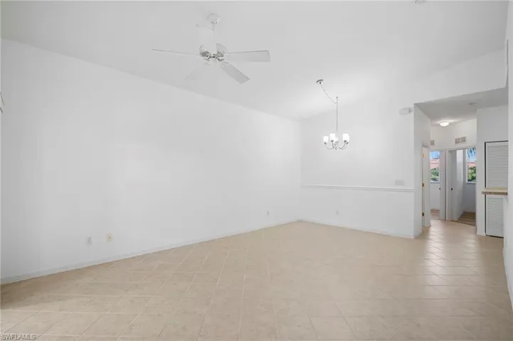 Unfurnished room with lofted ceiling, hanging lights, a ceiling fan, and light tile patterned floors