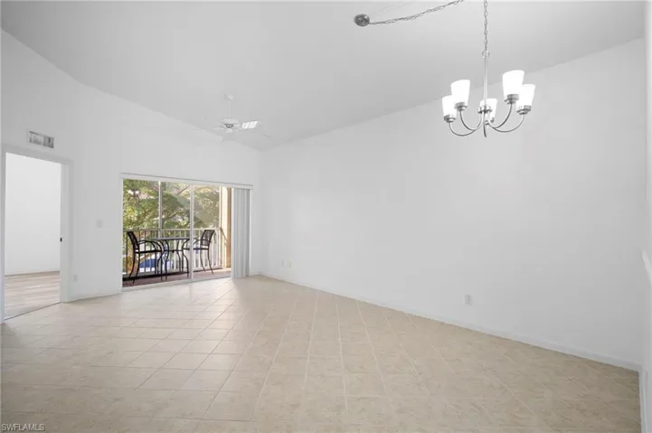 Empty room featuring vaulted ceiling, a ceiling fan, and hanging lights