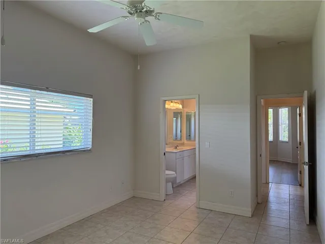 Unfurnished bedroom with light tile patterned floors, baseboards, a high ceiling, ceiling fan and jack and jill bathroom.
