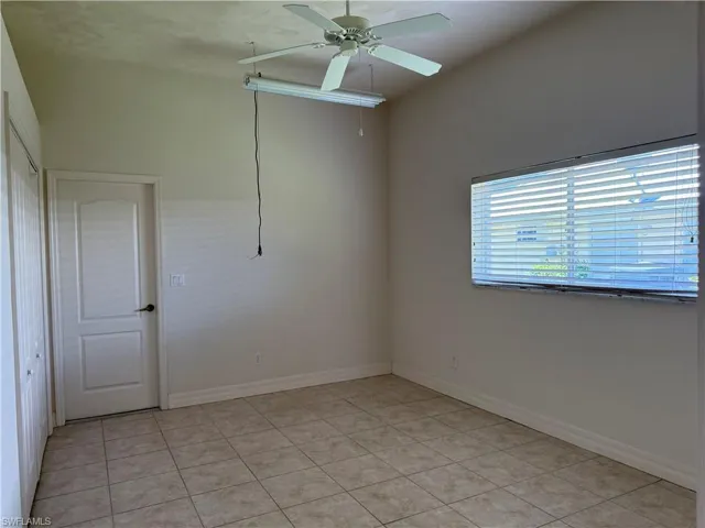 Empty room featuring light tile patterned floors and a ceiling fan