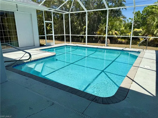 Pool featuring screen enclosure and a patio area