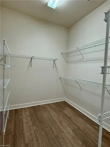 Spacious Walkin closet featuring dark wood-style floors in master bedroom.