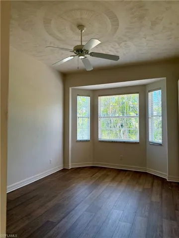 Bedroom dark wood-style floors, ceiling fan, and plenty of natural light.