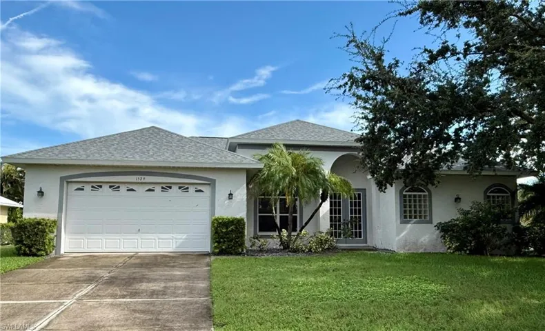 Ranch-style house featuring a shingled roof, stucco siding, concrete driveway, and a front lawn