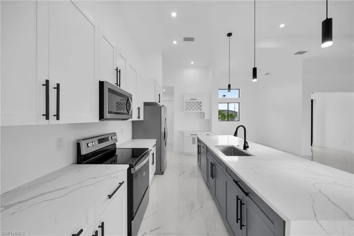 Kitchen with white cabinetry, stainless steel appliances, pendant lighting, sink, and light tile flooring