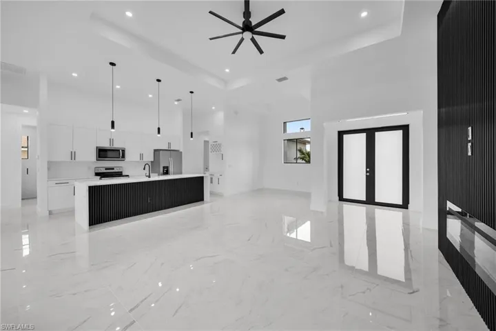 Kitchen with appliances with stainless steel finishes, white cabinetry, light tile floors, and a tray ceiling