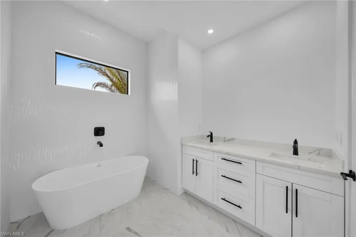 Bathroom featuring tile floors, dual bowl vanity, and a bath to relax in