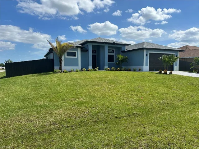 View of front facade featuring a garage and a front lawn