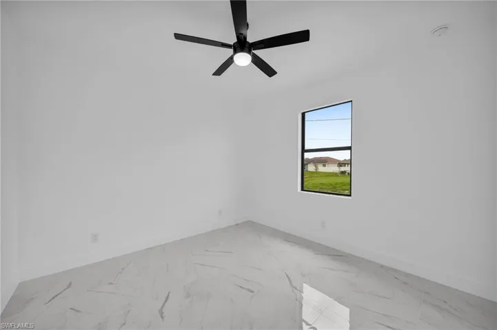 Unfurnished room with ceiling fan and light tile floors