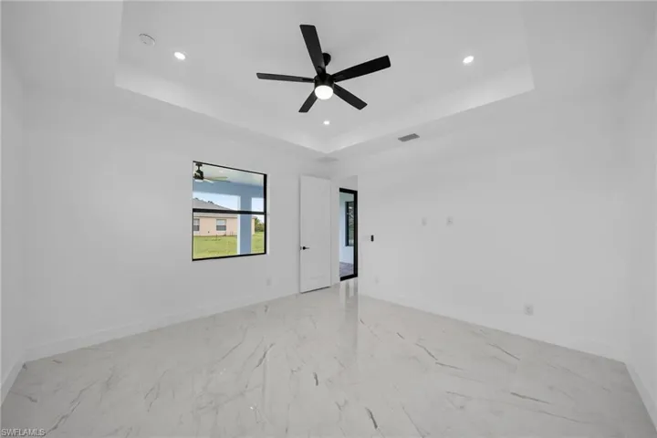 Tiled empty room with ceiling fan and a raised ceiling