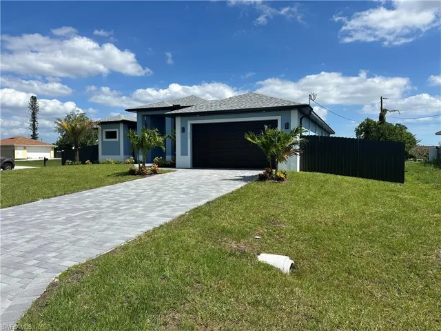 View of front facade featuring a garage and a front lawn